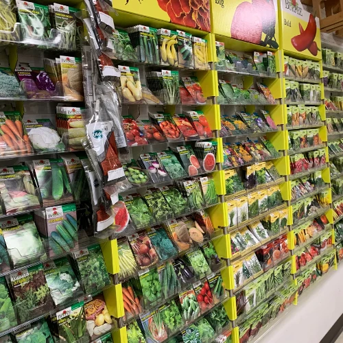 Store shelf stocked with colorful bags of organic potting mix, peat moss, perlite, vermiculite, orchid soil, and African violet soil.