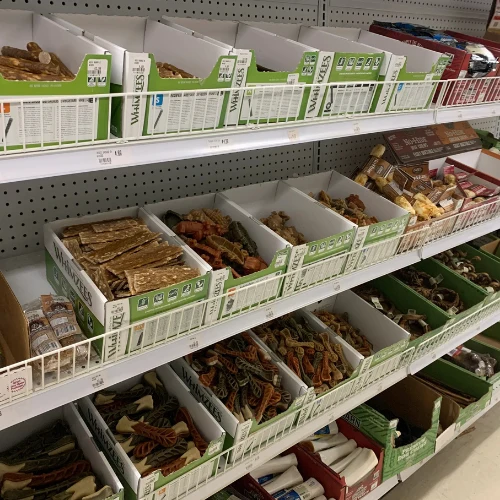 A brightly lit grocery store wall displays rows of colorful packaged seeds and gardening products, creating a busy, cheerful market-like scene.