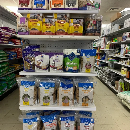 Grocery store shelves display assorted wood-smoking chips, including hickory, cherry, pecan, and apple, in colorful bags against a pegboard.